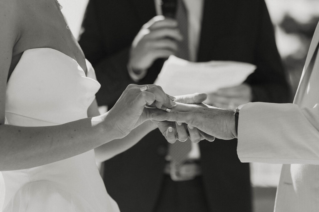 Close up of bride sliding wedding ring onto grooms finger during ceremony at the Landing Tahoe Resort