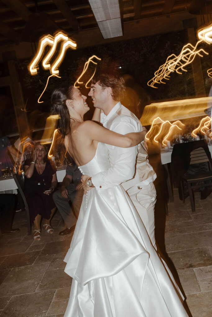 Wedding couple holding and smiling at each other with blurry lights and guests cheering in background at the Landing Tahoe Resort