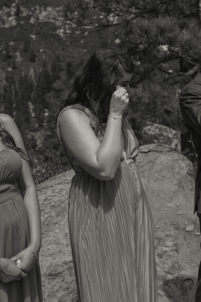 Elopement guest emotional during ceremony in Lake Tahoe with rocks and pine trees in background