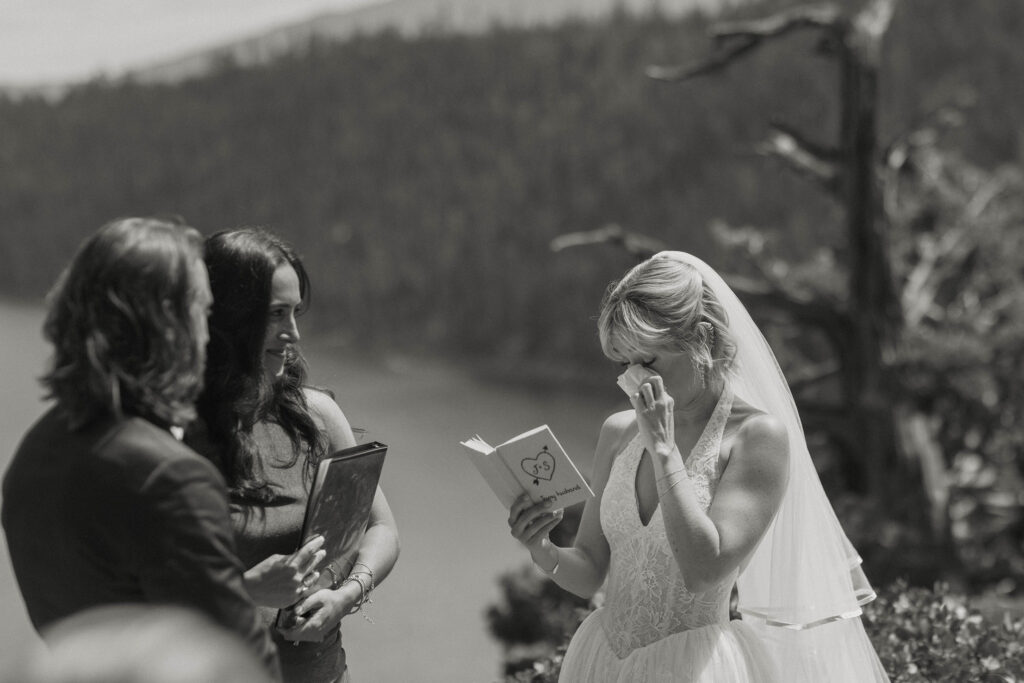 Bride emotional and wiping tears while reading vows from vow book during elopement ceremony in Lake Tahoe