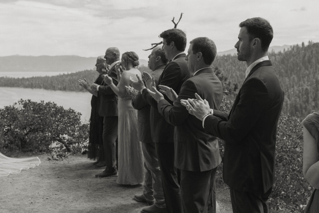 Elopement guests clapping after ceremony in Lake Tahoe with mountains of pine trees in background