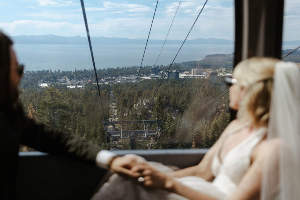 Elopement couple riding up Heavenly gondola while holding hands and looking out window towards Lake Tahoe