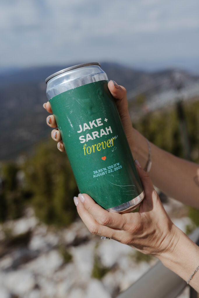 Close up of bride holding custom printed beer can with elopement couple's name and wedding date in Lake Tahoe