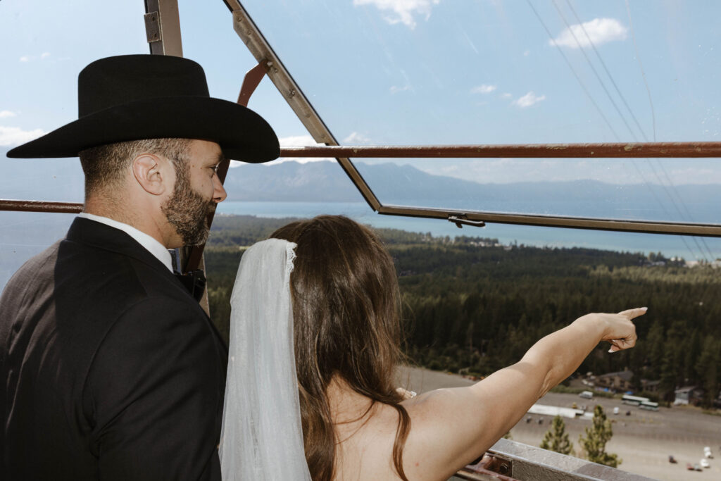 Wedding bride pointing while couple looks out window of cable car together at forest of pine trees and Lake Tahoe at Heavenly Lake View Lodge