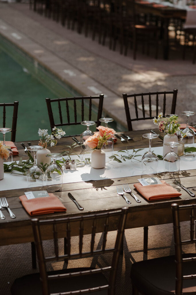 Wedding reception table with colorful floral decorations and napkins on dark wooden tables at PlumpJack Inn