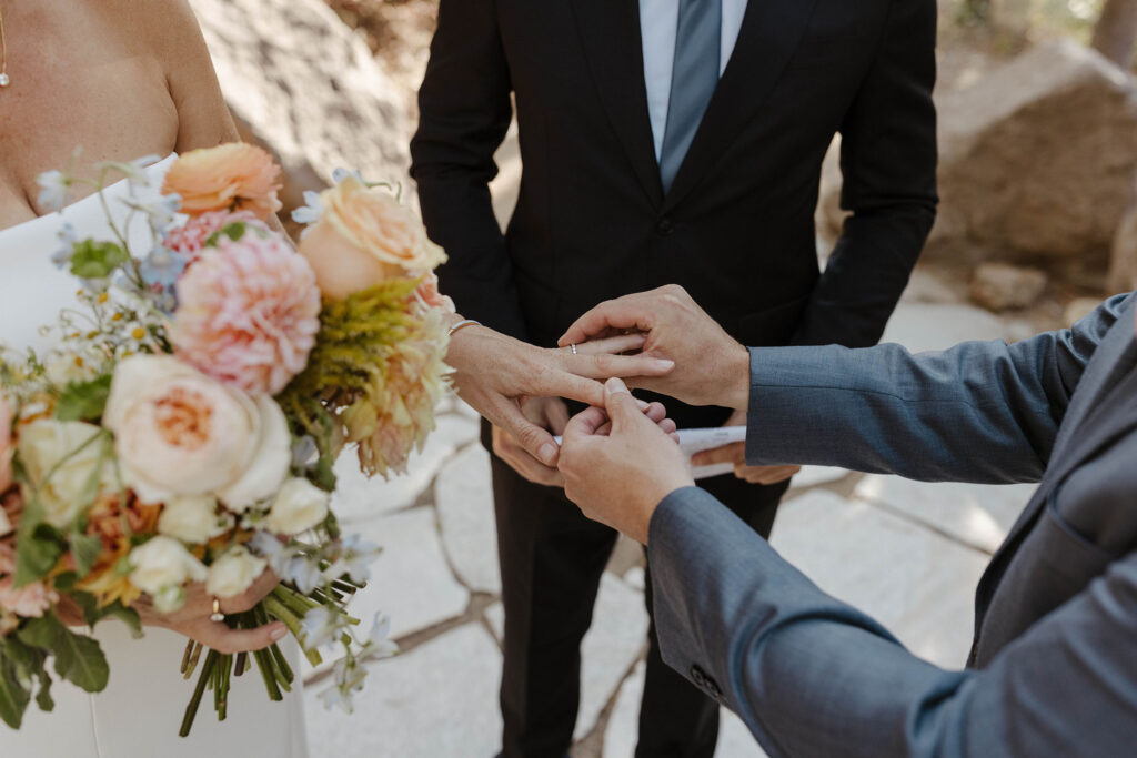 Groom sliding wedding ring onto bride's finger during ceremony at the PlumpJack Inn