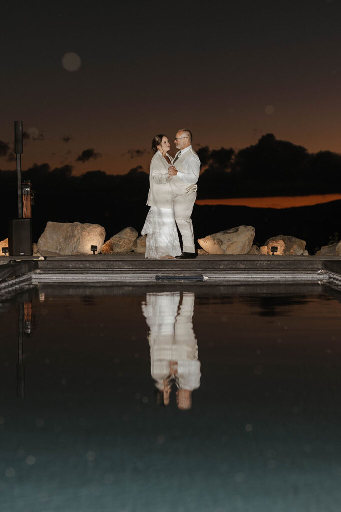 Bride dancing with her dad at end of pool during wedding reception at Austin Ridge Truckee with large rocks at sundown