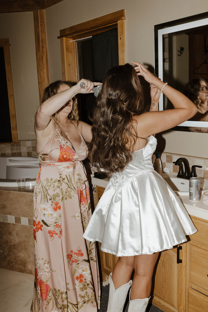 Bride changing out of wedding dress into reception dress while mom brushes out her hair at Austin Ridge Truckee