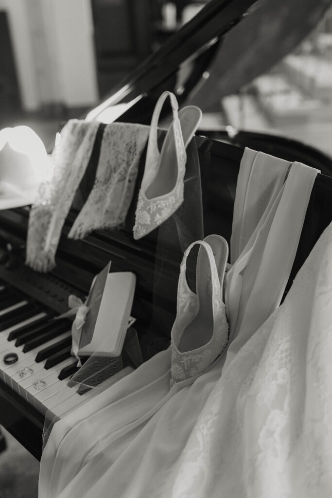 Bride's shoes and vow book sitting on piano next to wedding dress and rings at Austin Ridge Truckee