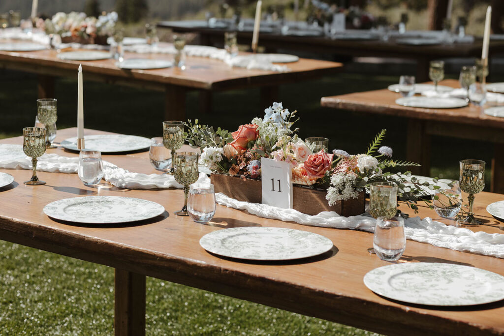 Colorful floral arrangement on wedding reception table next to white plates and glassware at Austin Ridge Truckee