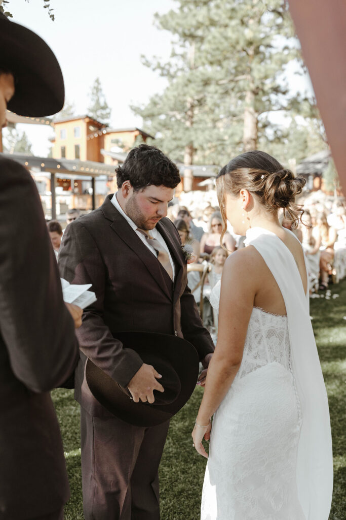 Wedding couple standing together with heads bowed while officiant reads during ceremony at Austin Ridge Truckee