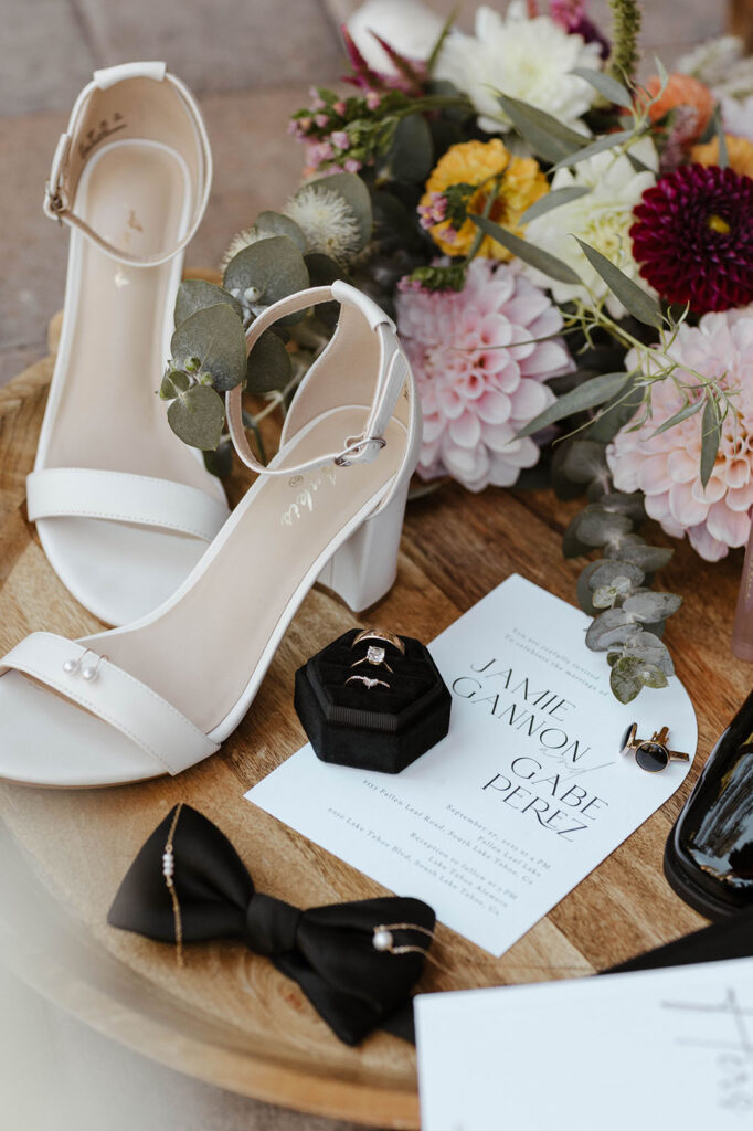 Bride's shoes and floral bouquet in flat lay with wedding rings on wooden table in Lake Tahoe