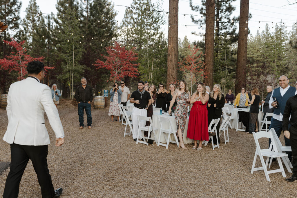 Guests standing and clapping while elopement couple walks into reception surrounded by trees in Lake Tahoe