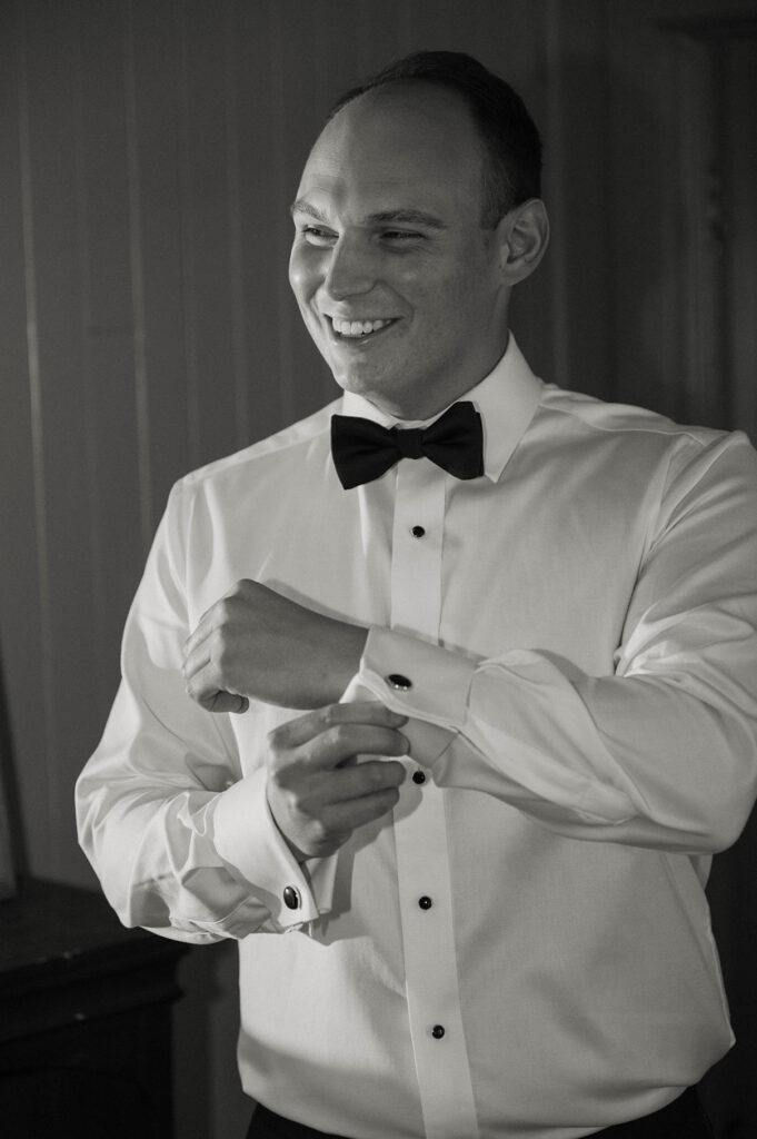 Wedding groom buttoning cuff links on dress shirt while smiling at Valhalla Tahoe