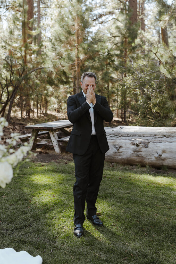 Bride's dad emotional during first look with large log and pine trees in background at Valhalla Tahoe