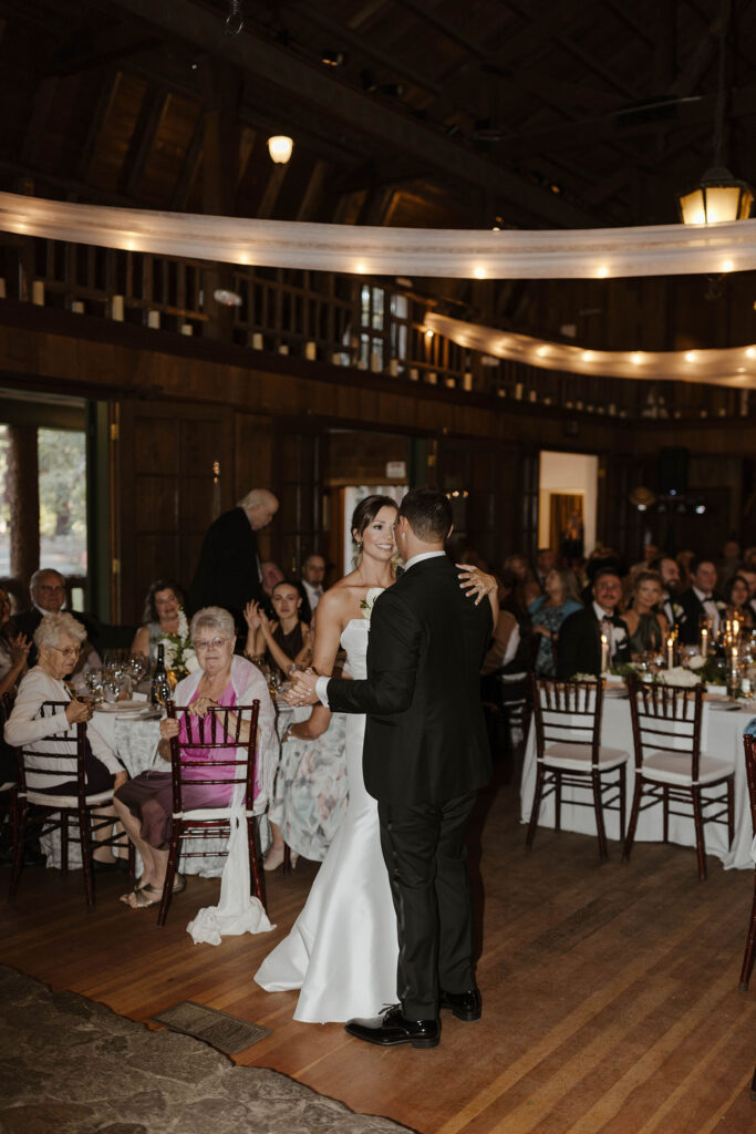Wedding couple dancing together on wooden floor during reception with guests watching at Valhalla Tahoe