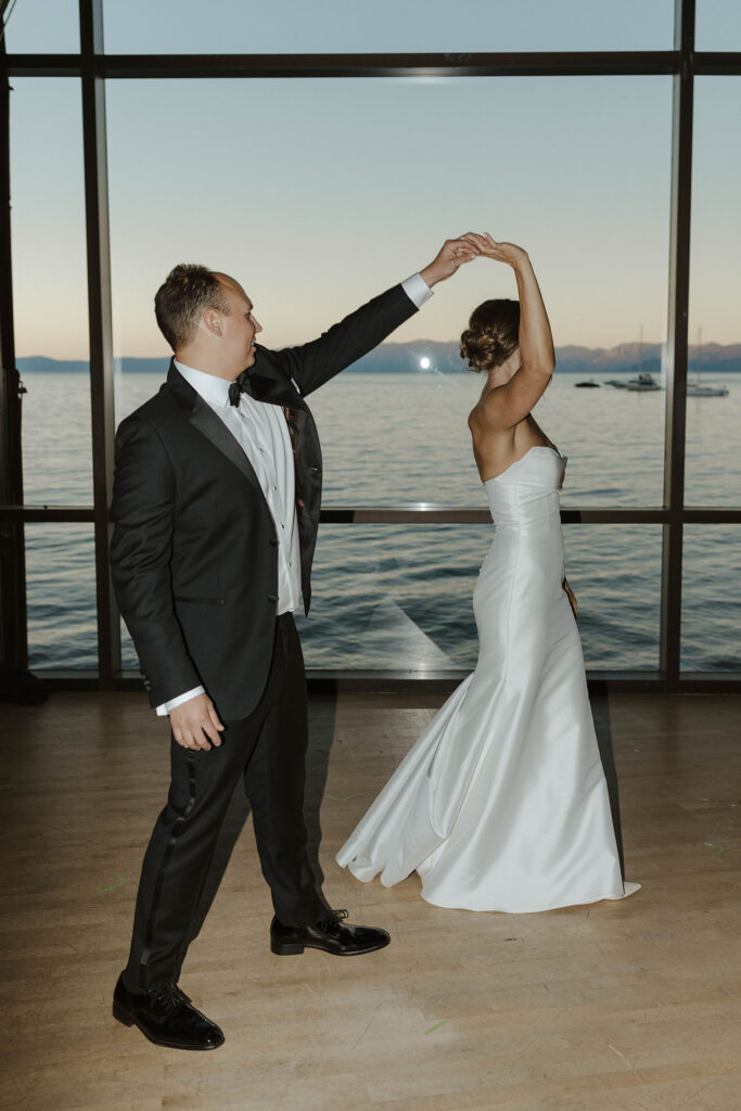 Wedding couple dancing together in front of large windows at Valhalla with Lake Tahoe in background