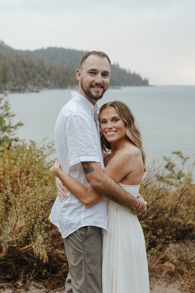 couple smiling at the camera with laketahoe in the background