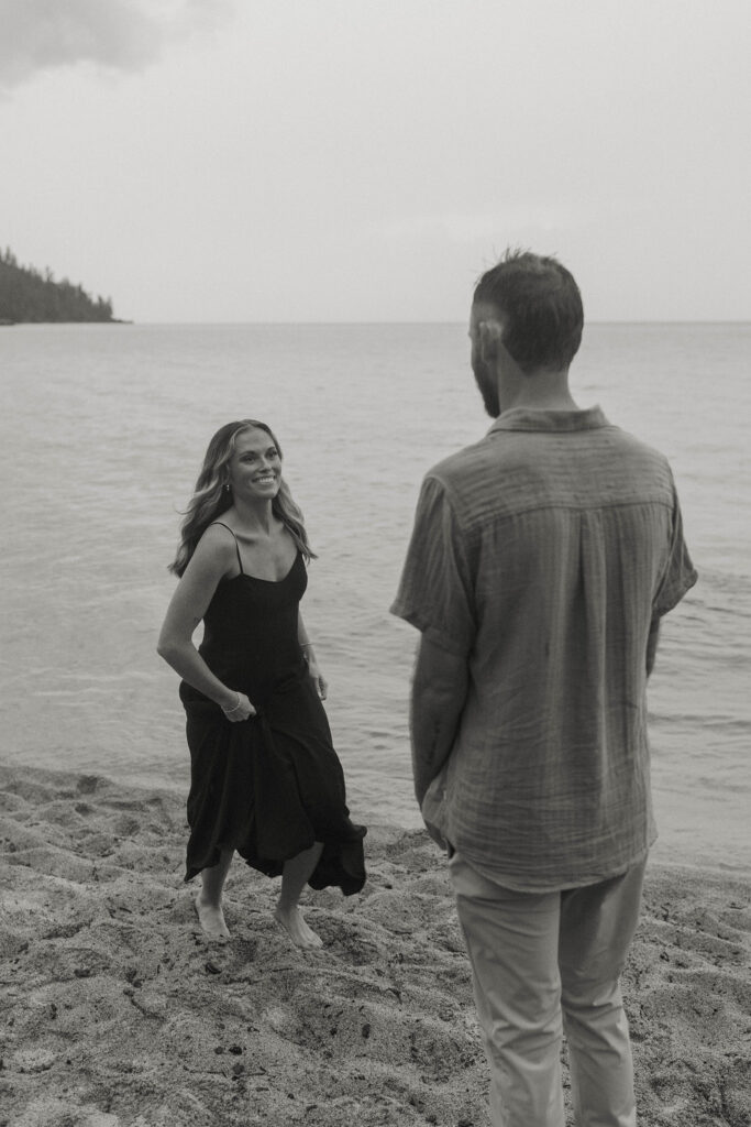 woman smiling and running up to her man barefoot on a beach in lake tahoe