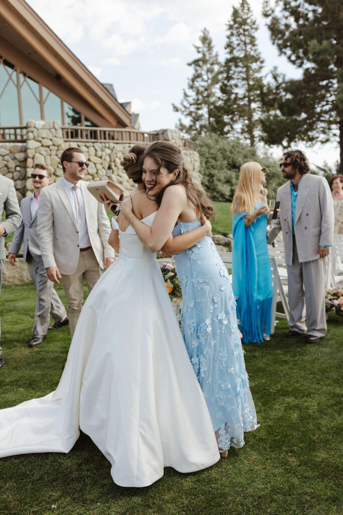 Bride hugging wedding guest with other guests in background at Edgewood