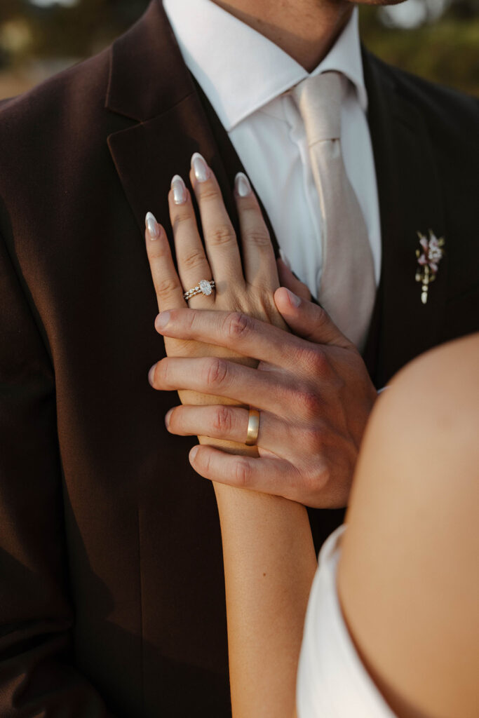 Close up of wedding couple's hands holding each other while wearing wedding rings at Edgewood Tahoe