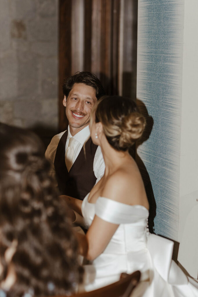 Groom smiling at bride while sitting at table during wedding reception at Edgewood Tahoe