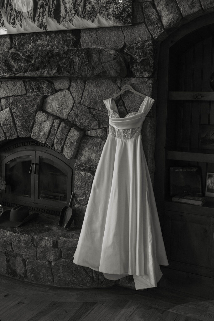 Elopement bride's dress hanging on stone fireplace mantle in Lake Tahoe