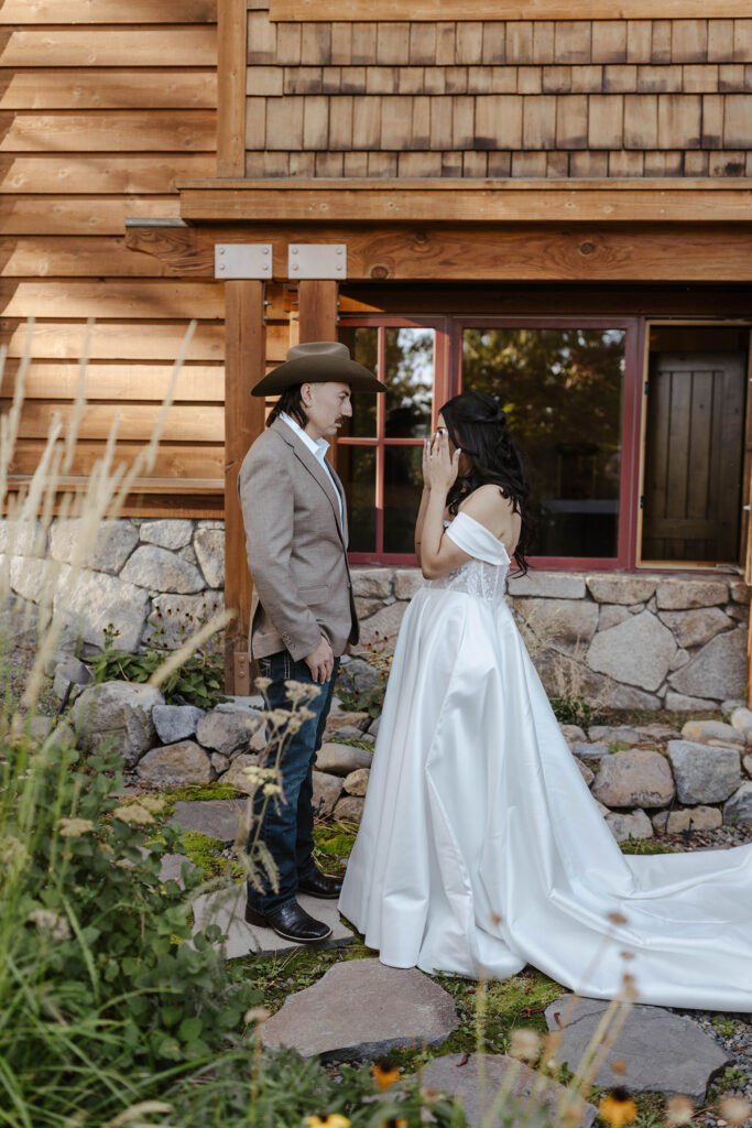 Bride emotional during elopement couple's first look in front of wooden building next to greenery in Lake Tahoe
