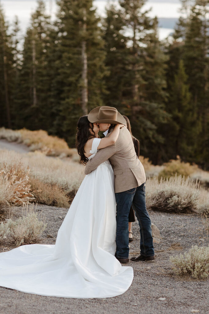 Elopement couple kissing and hugging each other after ceremony in Lake Tahoe with pine trees in background