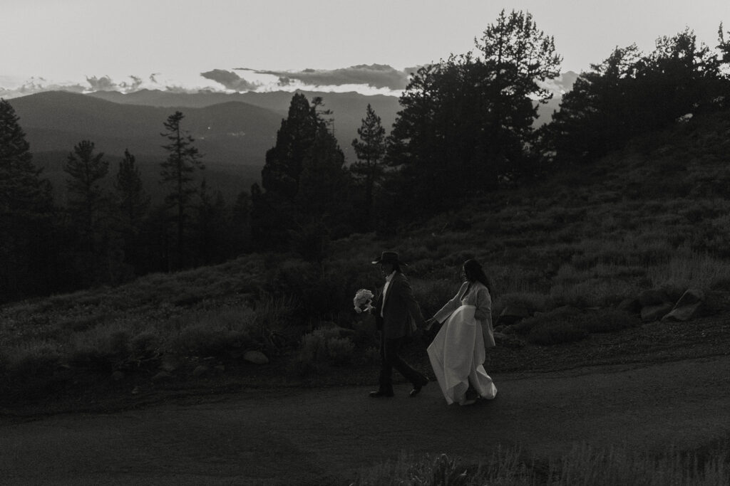 Elopement couple holding hands and walking along trail together with pine trees in background in Lake Tahoe