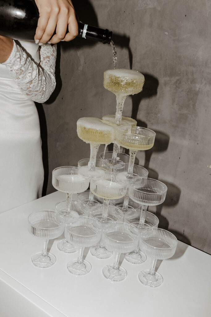 Elopement guest pouring champagne into tower of glasses during reception in Lake Tahoe