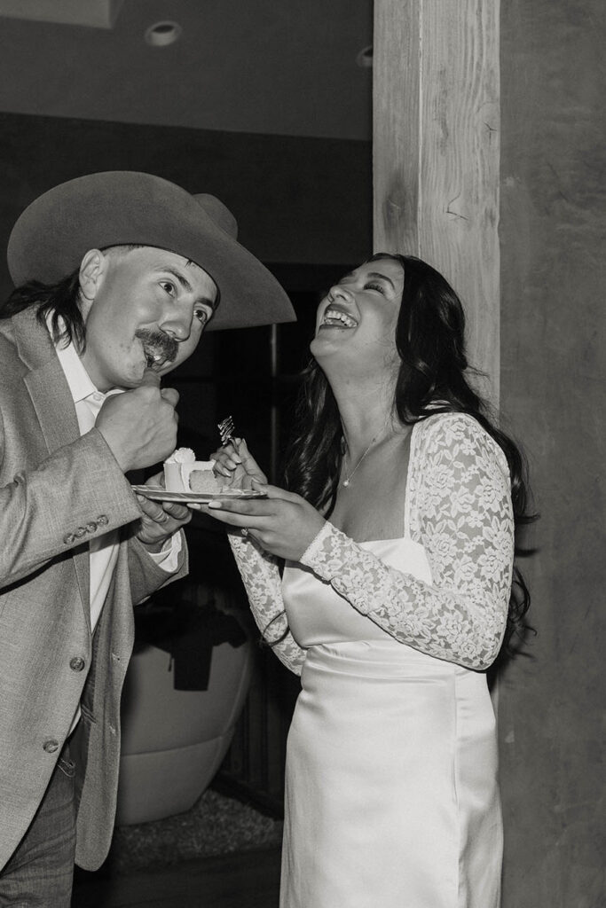 Bride laughing while groom takes a bite of cake during elopement reception in Lake Tahoe