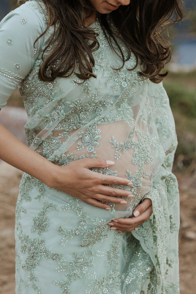 pregnant woman holding her belly in blue lace dress in lake tahoe