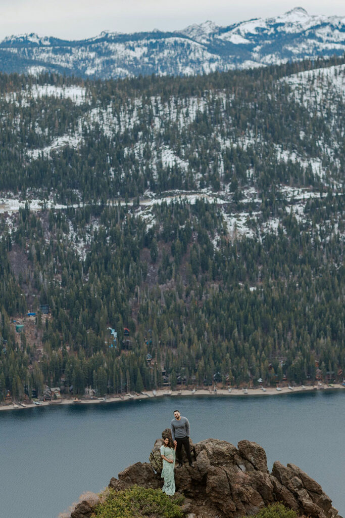 maternity couple holding hands standing on rocks overlooking lake tahoe