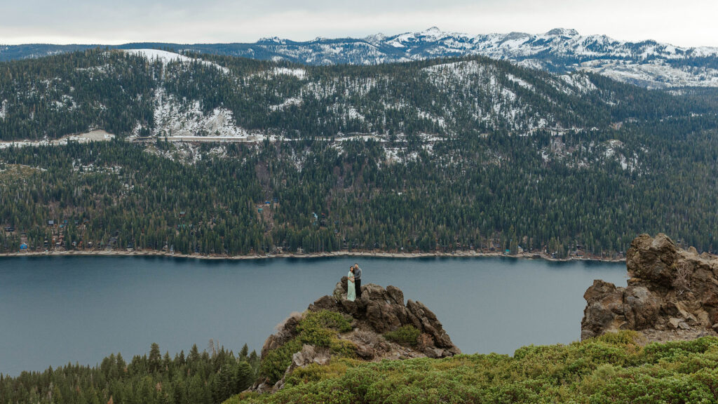 maternity couple holding hands standing on rocks overlooking lake tahoe