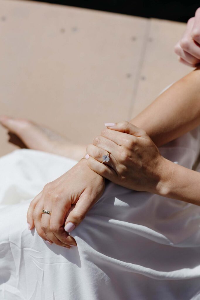 Close up of woman's hands wearing engagement ring while sitting on a pier in Emerald Bay