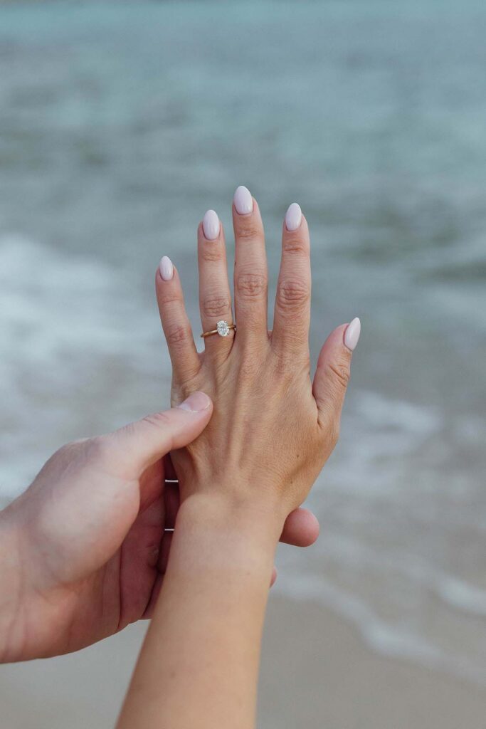 Close up of engagement couple's hands with engagement ring on woman's finger with Lake Tahoe in background