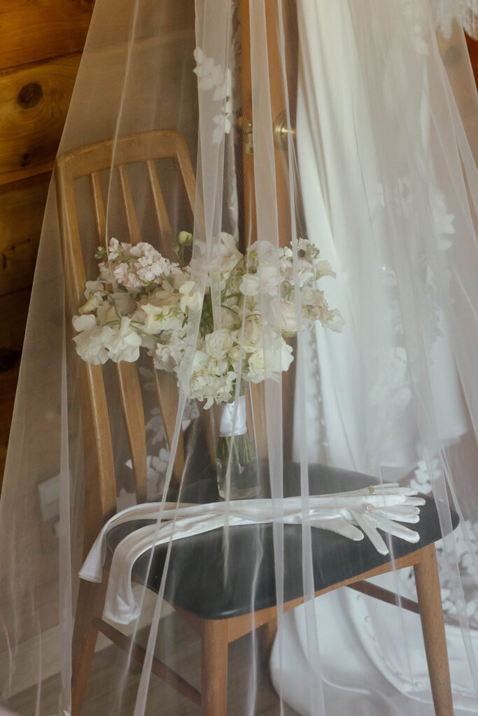 Wedding gloves and floral bouquet sitting on wooden chair covered by wedding veil at Garwoods Lake Tahoe