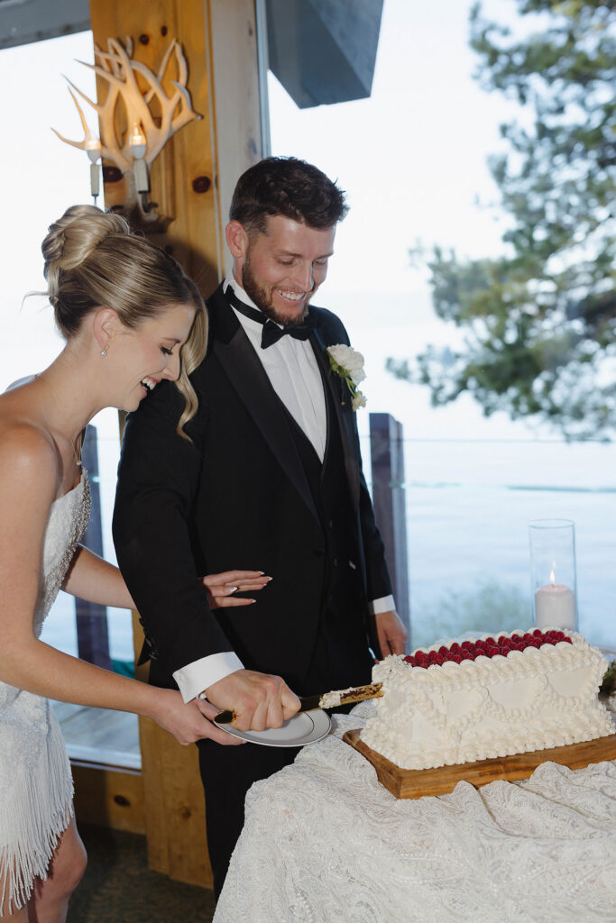 Groom holding knife and cutting wedding cake while bride holds plate while both smile at Garwoods at Lake Tahoe