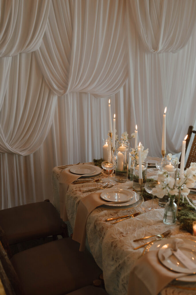 Wedding dinner table with lit candles and silky curtains in background at Garwoods at Lake Tahoe