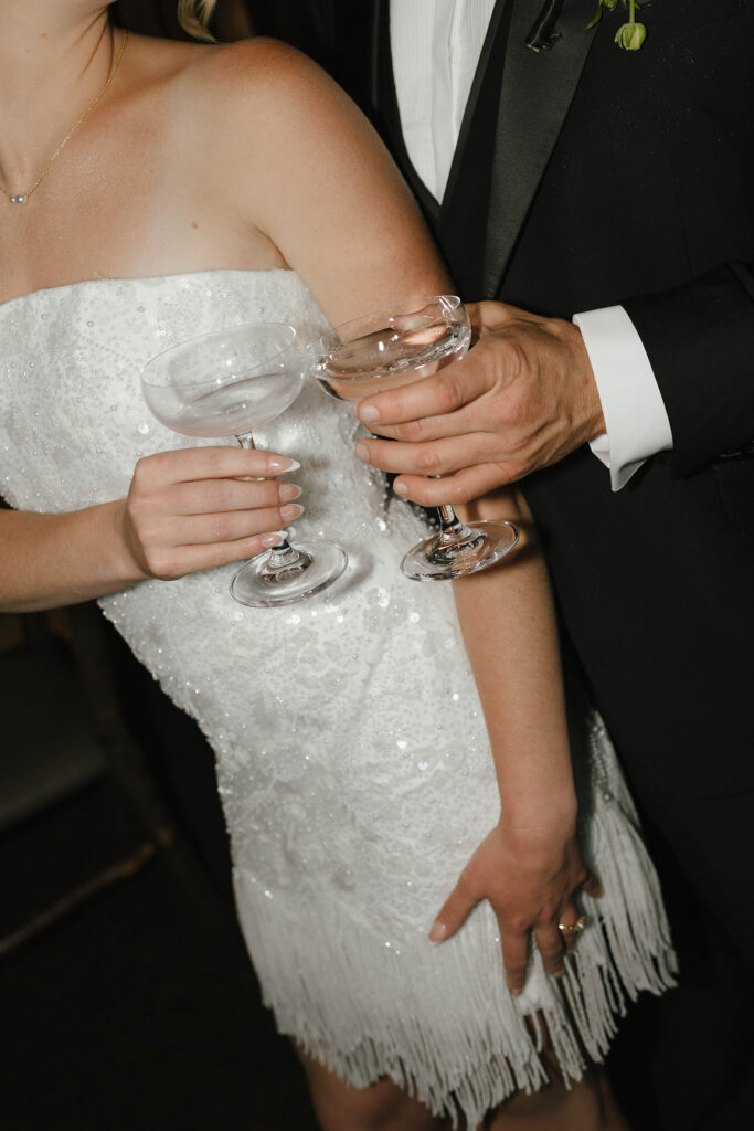 Close up of wedding couple cheering drinks while bride is wearing reception outfit at Garwoods Lake Tahoe