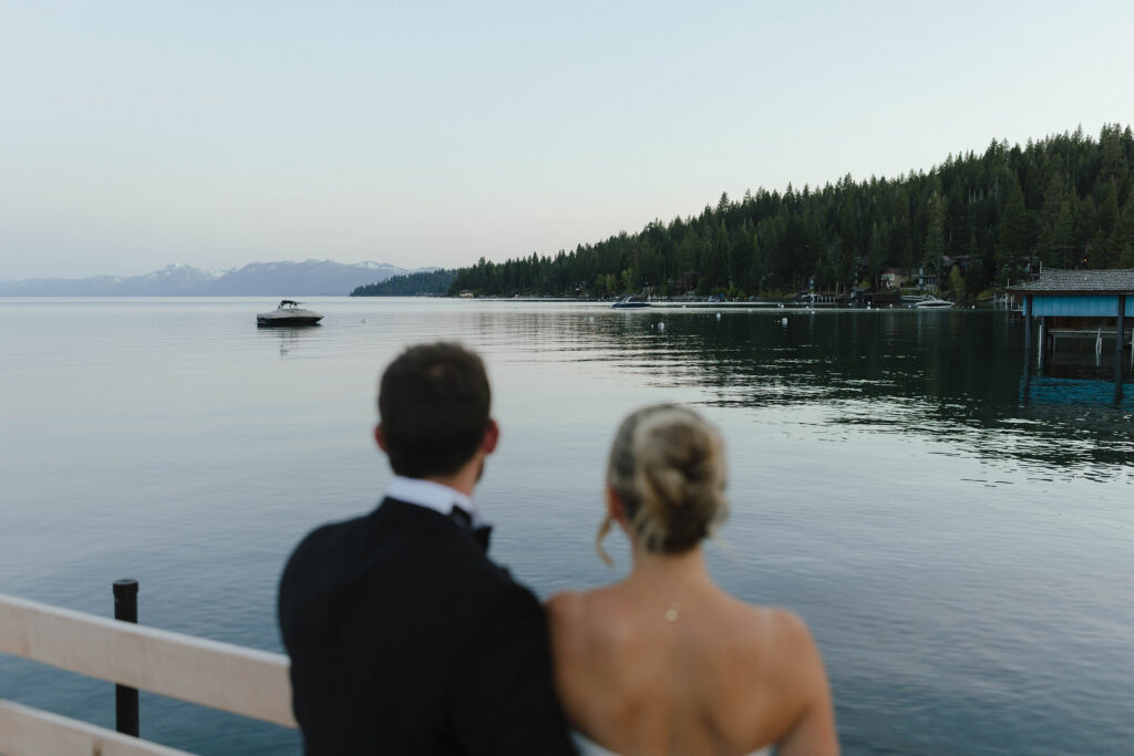 Wedding couple standing together on pier and looking out at Lake Tahoe