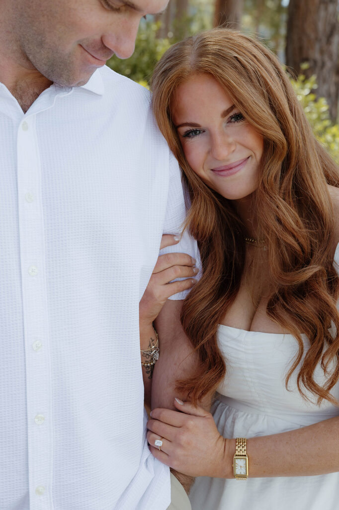 Close up of woman holding fiancé's arm while smiling and wearing engagement ring at Sand Harbor