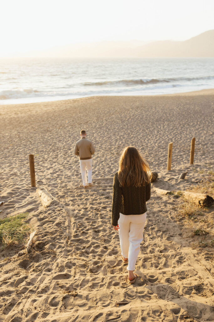 Couple walking down sandy stairs on the beach in San Fransisco for their engagement session