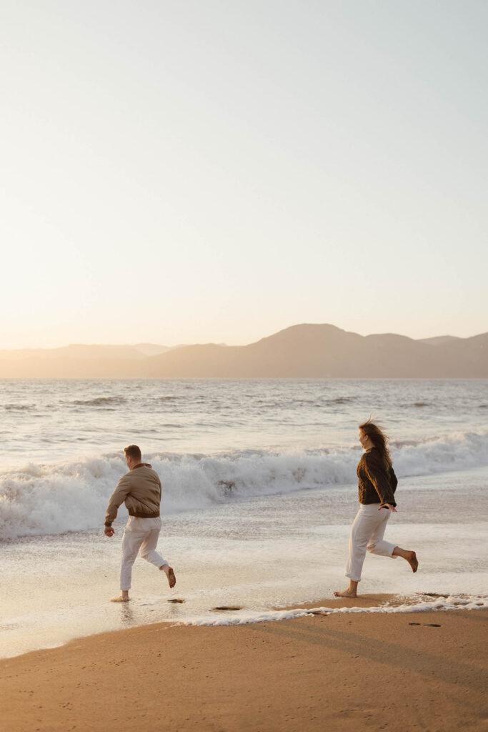 Couple running on the beach at sunset in San Fransisco