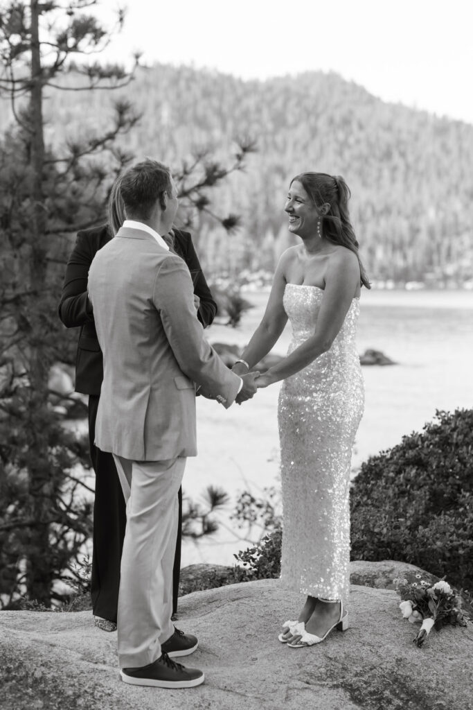 Elopement couple holding hands during ceremony with Lake Tahoe and forest of pine trees in background