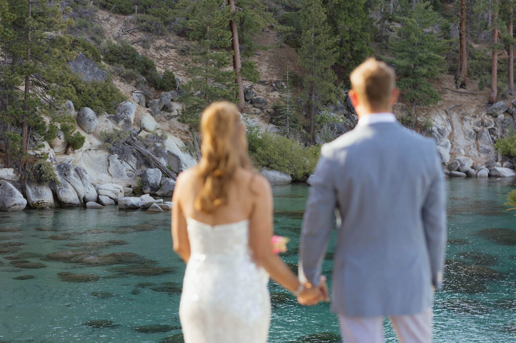 Elopement couple holding hands while looking out at Lake Tahoe together