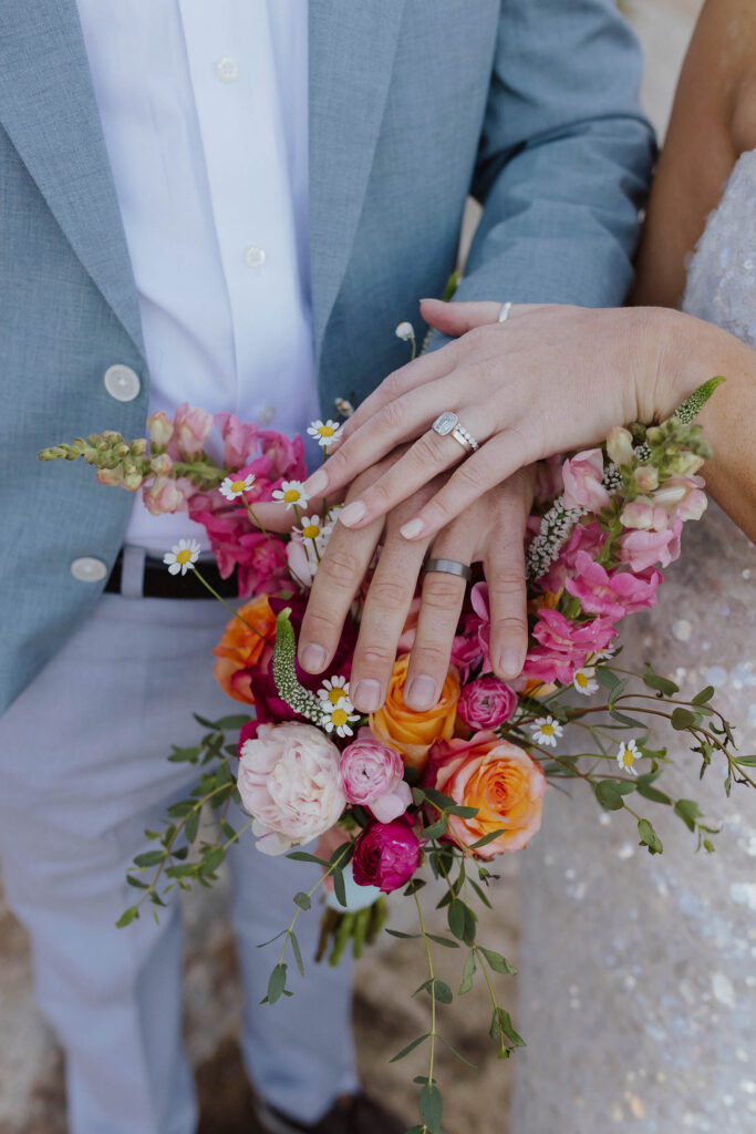 Close up of elopement couple's hands on top of floral bouquet while wearing wedding rings at Lake Tahoe