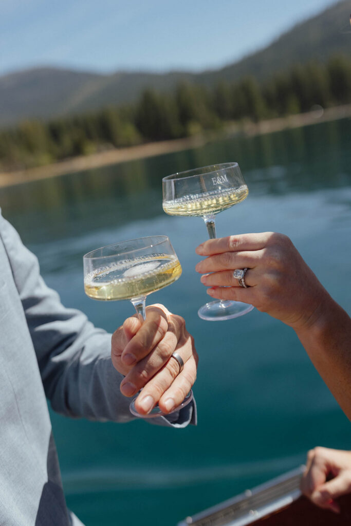 Elopement couple holding drinks together while wearing wedding rings on a boat in Lake Tahoe