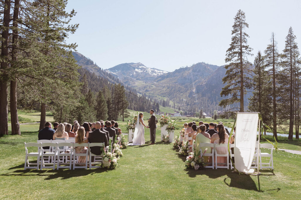 Overview of wedding ceremony in open field between pine trees at Everline Resort in Lake Tahoe with Lake Tahoe in background